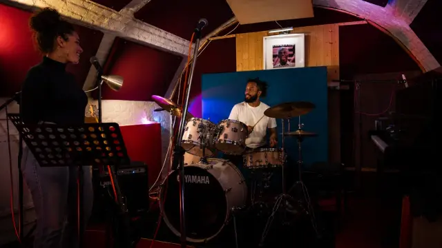 A singer and drummer rehearsing together in the studio
